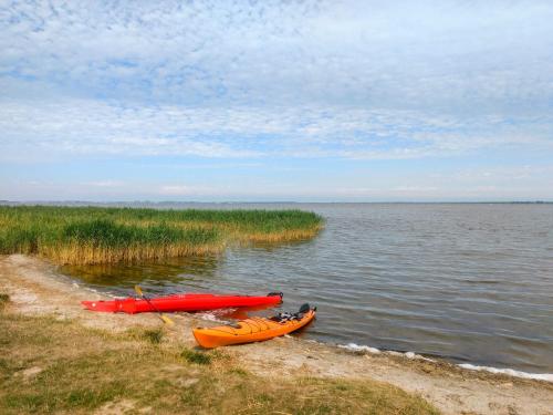 two kayaks on the shore of a body of water at Ferienhaus Bodden in Neuendorf