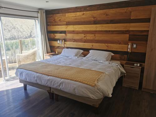 a bedroom with a large bed with a wooden wall at Lodge Nueva Elqui in Pisco Elqui