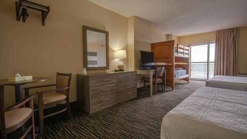 Habitación de hotel con cama, escritorio y TV. en Americana Motor Inn on Boardwalk en Ocean City