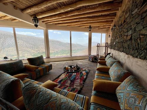 a living room with couches and a stone wall at Touda Ecolodge Atlas Mountains in Zawyat Oulmzi