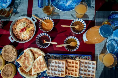 a table with plates of food and cups of orange juice at Touda Ecolodge Atlas Mountains in Zawyat Oulmzi