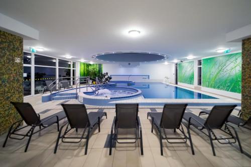 una piscina con sillas y una mesa en una habitación en Napfeny Hotel, en Zalakaros
