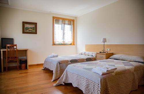a hotel room with two beds and a window at A Lúa do Camiño in Melide