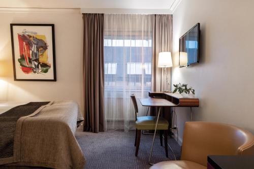 a hotel room with a bed and a desk and a window at Elite Hotel Stockholm Plaza in Stockholm