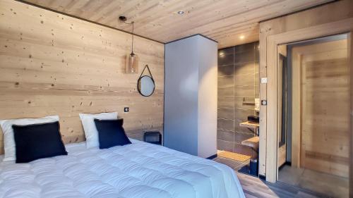 a bedroom with a large bed with a wooden wall at Chalet BAS-THEX 8-10 pers SAINT JEAN D'AULPS- PROCHE MORZINE-WIFI in Saint-Jean-dʼAulps