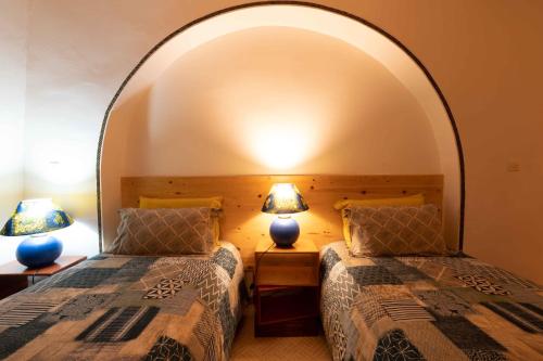 two beds in a room with an arch over them at Touda Ecolodge Atlas Mountains in Zawyat Oulmzi