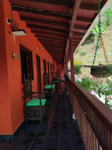 a porch of a house with orange walls and green benches at Hotel Orillas del Pizano in Jardin