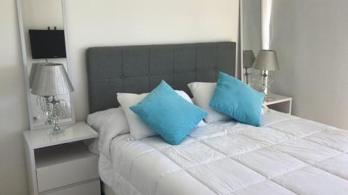 a bedroom with a white bed with blue pillows at Gala Vista in Punta del Este