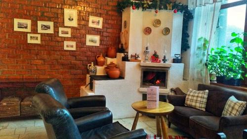 a living room with leather chairs and a fireplace at Pension Casa cu Tei in Sărata-Monteoru
