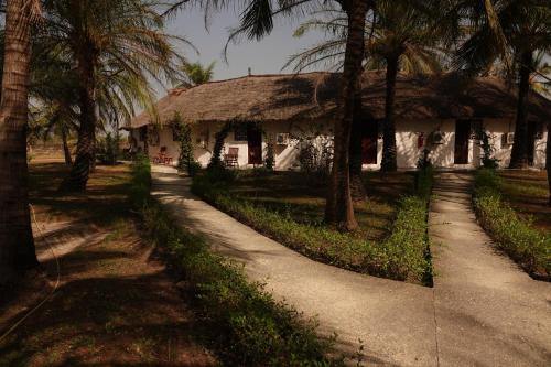 a house with a thatched roof and palm trees at Hôtel Katakalousse in Yembakana
