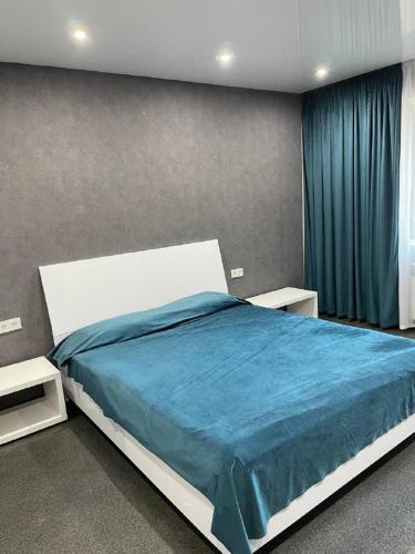 een slaapkamer met een groot bed en een blauwe deken bij Люкс апартаменты, Кривой Рог, 5й Заречный, Покровский район in Krivoy Rog