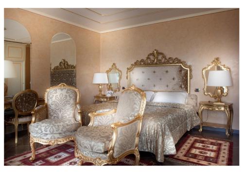 a bedroom with a bed and a pair of chairs at Park Hotel Ville Montefiori in Gardone Riviera