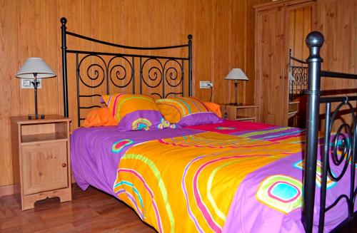 - une chambre avec un grand lit et une couette colorée dans l'établissement Pedrazales Rural, à Pedrazales