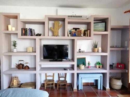 a living room with white shelves and a tv at Casa La Pizarra in Bubión