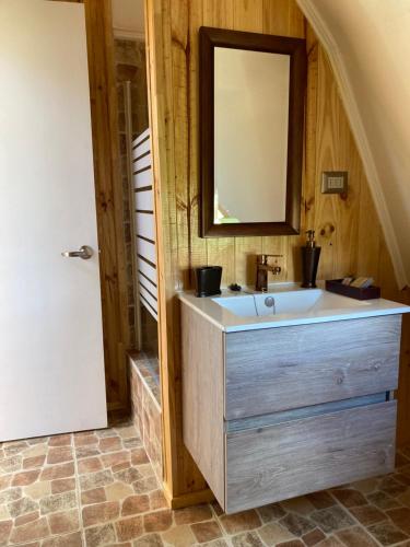 La salle de bains est pourvue d'un lavabo et d'un miroir. dans l'établissement Domos Puerto Varas, à Puerto Varas