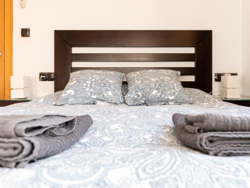 a bed with two pillows and towels on it at Apartamento Esparteria Parking gratuito in Córdoba