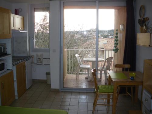 une cuisine avec une porte s'ouvrant sur un balcon avec une table dans l'établissement Les Chênes Blancs, à Gréoux-les-Bains