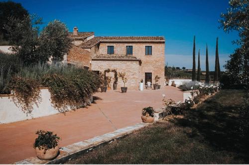 ein großes Backsteingebäude mit einem Hof mit Topfpflanzen in der Unterkunft Villa Mozzafiato con Jacuzzi o Camino Toscana Montepulciano in Valiano