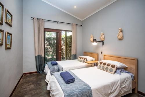 two beds in a room with a window at Summerfields Rose Retreat and Spa in Hazyview