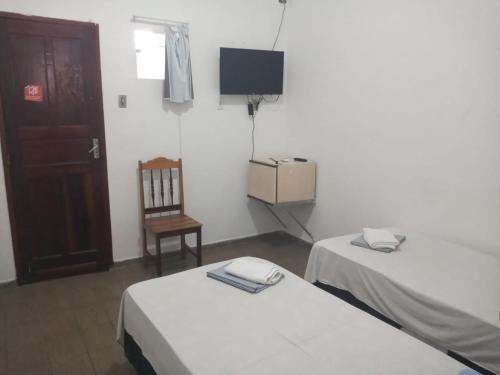 a room with two beds and a chair and a television at Pousada Maré Mansa in Maceió