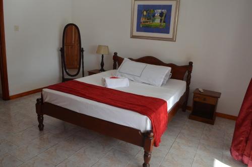 sypialnia z łóżkiem z czerwonym kocem w obiekcie Touchdown Villa w mieście Pointe Larue