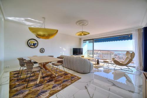 - un salon avec une table, des chaises et une grande fenêtre dans l'établissement Cannes Luxury Rental - Magnificent Apartment With Sea View, à Cannes