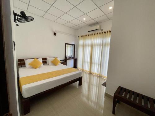 a bedroom with a bed with yellow pillows and a window at Theon Resort in Anuradhapura