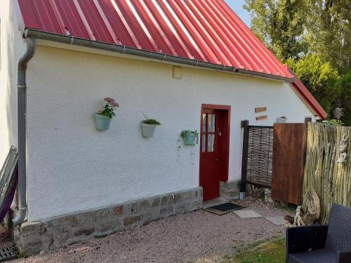 a white building with a red roof and a red door at Petite maison Normande in Bellou-en-Houlme