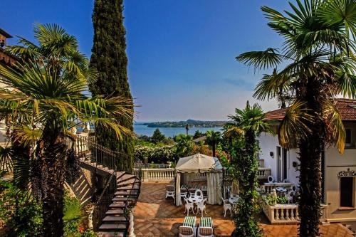 a resort with palm trees and a view of the water at Park Hotel Ville Montefiori in Gardone Riviera
