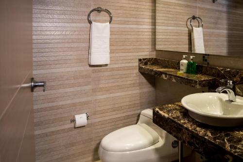 a bathroom with a toilet and a sink at Hotel Plaza Suites in Bogotá