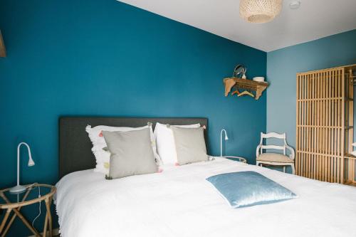 een slaapkamer met blauwe muren en een bed met witte kussens bij Hoeve de Reetjens - Le Grenier in Bilzen