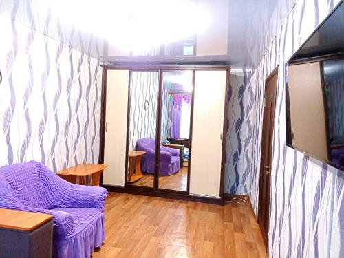 a living room with a purple chair and a mirror at Уютные апартаменты c кондиционером на Уманчанке in Umanʼ