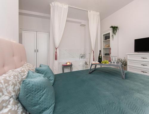 a bedroom with a bed with blue pillows and a television at Apartamenty Centrum II in Bydgoszcz