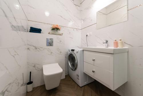a white bathroom with a washing machine and a sink at Apartamenty Centrum II in Bydgoszcz