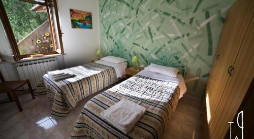 two beds in a room with a mural on the wall at casaemilia2 in Tuoro sul Trasimeno
