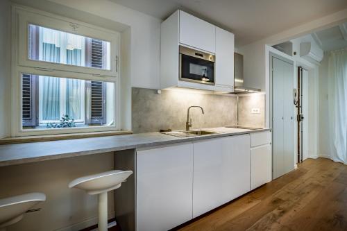 una cucina con armadi bianchi, lavandino e due finestre di JCL first apt in the hearth of Florence a Firenze