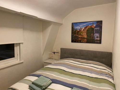 een slaapkamer met een bed met een foto aan de muur bij Cosy little house in Brugge