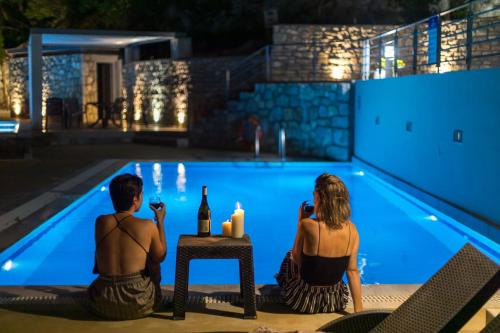 a man and a woman sitting in front of a swimming pool at Thealos Village aparthotel Lefkada in Lygia