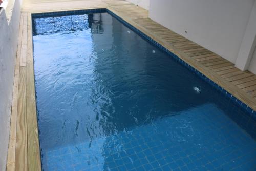 a large blue swimming pool with a wooden deck at Innbox - Canasvieiras 2 in Florianópolis