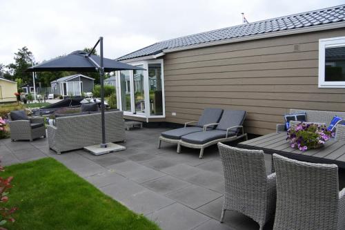 eine Terrasse mit Stühlen, einem Tisch und einem Sonnenschirm in der Unterkunft Watervriend in Earnewâld