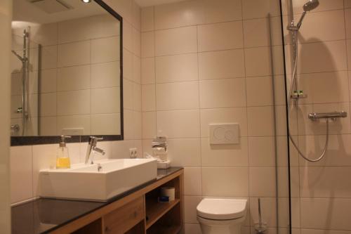 a bathroom with a sink and a shower and a toilet at Hotel Garni Lärchenhof in Lech am Arlberg