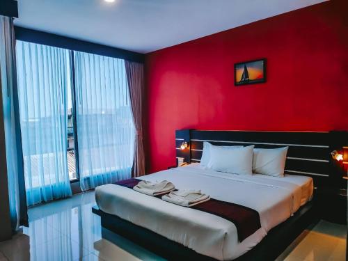 a red bedroom with a bed with two towels on it at The Harbour Front Hotel in Suratthani