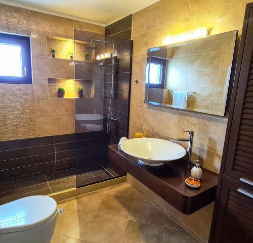 W łazience znajduje się umywalka, toaleta i lustro. w obiekcie Evdokia Beach Resort w mieście Gázion