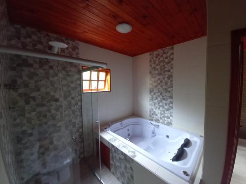 a bathroom with a tub and a glass shower at Recanto Três Irmãs, chalé 2 in Camanducaia