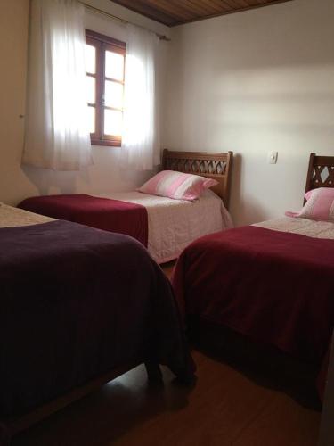 a bedroom with two beds and a window at Suítes Refúgio do Sossego - Campos do Jordão in Campos do Jordão