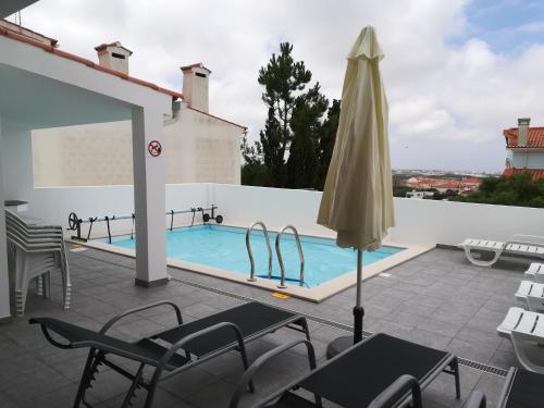 a patio with an umbrella and a swimming pool at PoolSeaView Spacious House in Atouguia da Baleia