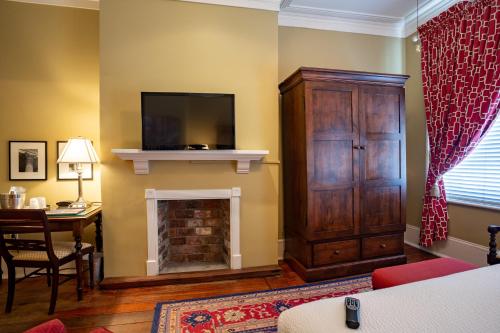 a living room with a fireplace and a tv on a wall at The Marshall House, Historic Inns of Savannah Collection in Savannah