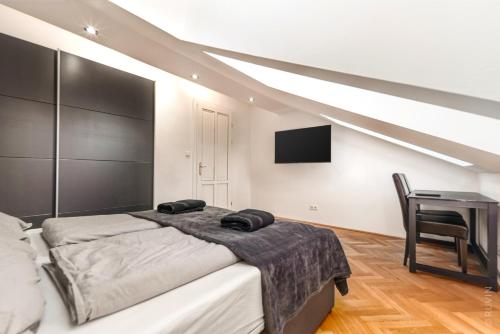 a bedroom with a bed and a desk and a tv at Designer Apartments, 2 min to U1 Reumannplatz in Vienna