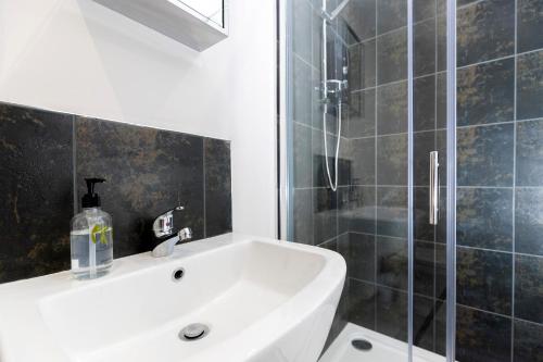 La salle de bains est pourvue d'un lavabo blanc et d'une douche. dans l'établissement Avery House 2 - Two Bedroom with Outdoor Terrace by BPNE, à Darlington