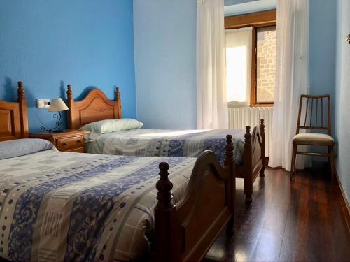 een blauwe slaapkamer met 2 bedden en een stoel bij Apartamento Rural Areso - Fraxkuenea in Areso